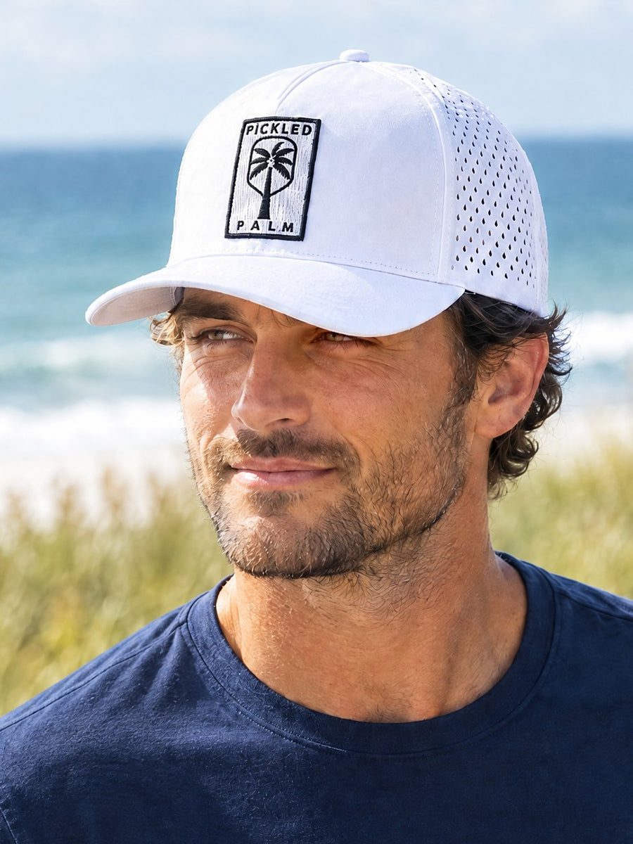 Close-up of The Whitecap white performance hat on a player at the beach